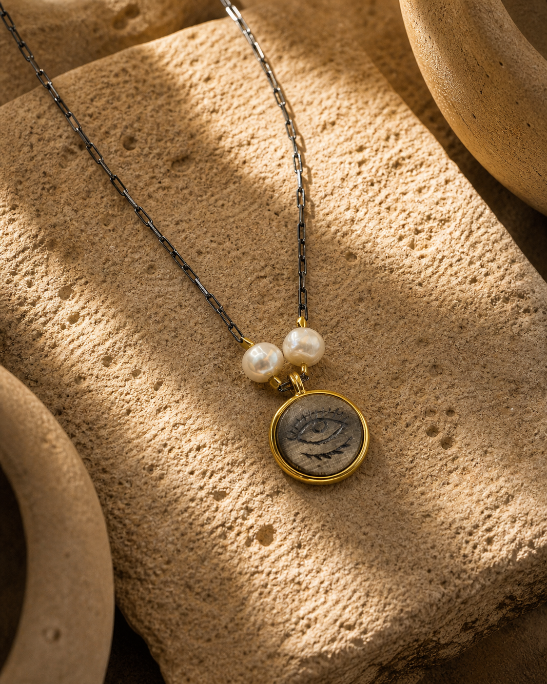 Pearl detailed silver eye pendant necklace on natural stone surface