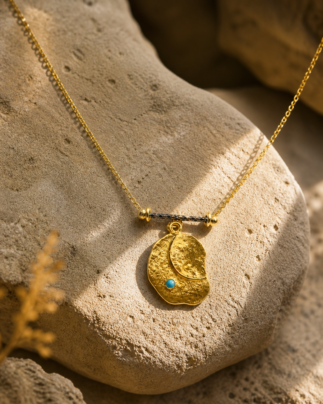Turquoise detail gold-plated silver pendant necklace with organic textured charm on natural stone surface